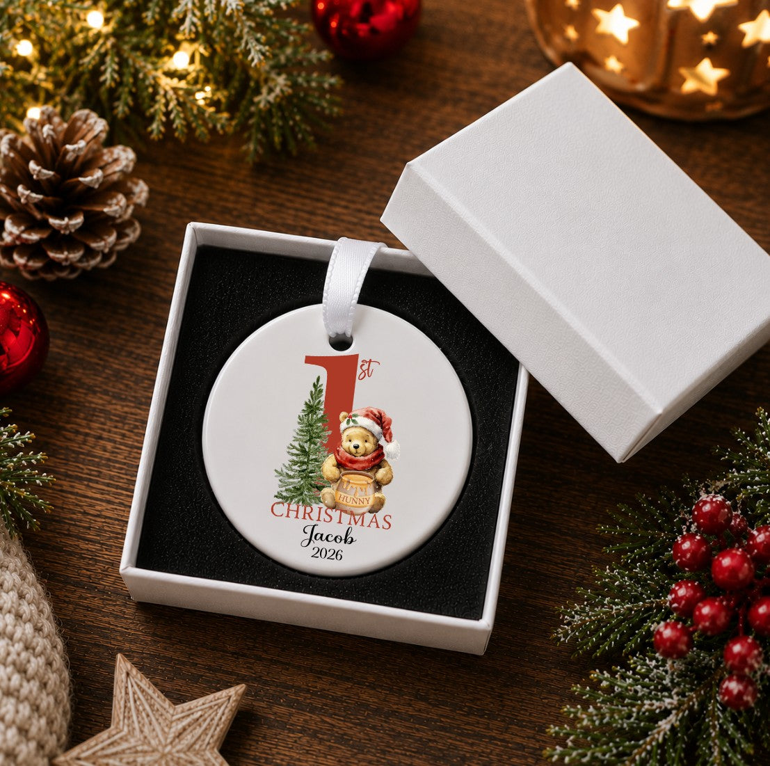 A round personalised Christmas ornament displayed in an open white gift box on a wooden table, 