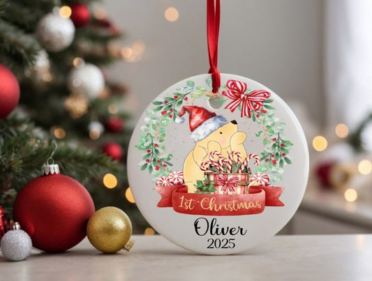 Personalised Christmas ornament with a teddy bear and festive design, placed in front of a decorated Christmas tree.