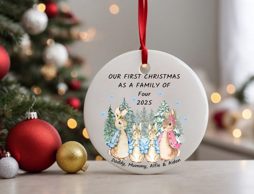 Personalised Christmas ornament with family of four and tree, in front of a decorated Christmas tree.