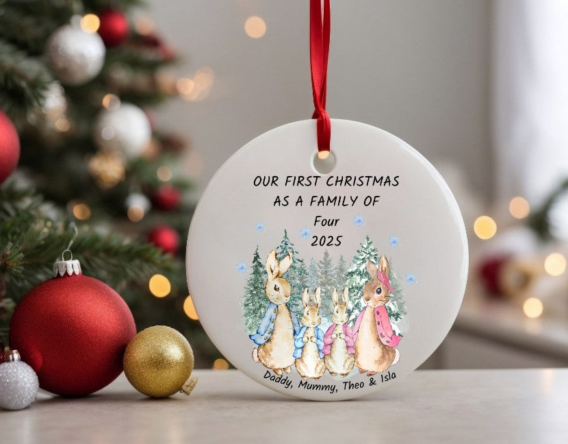 Decorative Christmas ornament with family of bunnies and personalised text in front of a Christmas tree.
