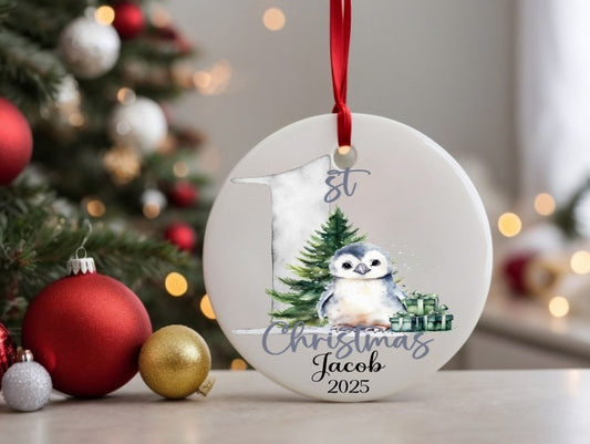 Personalised Christmas ornament with a penguin and tree design, hanging in front of a decorated Christmas tree.