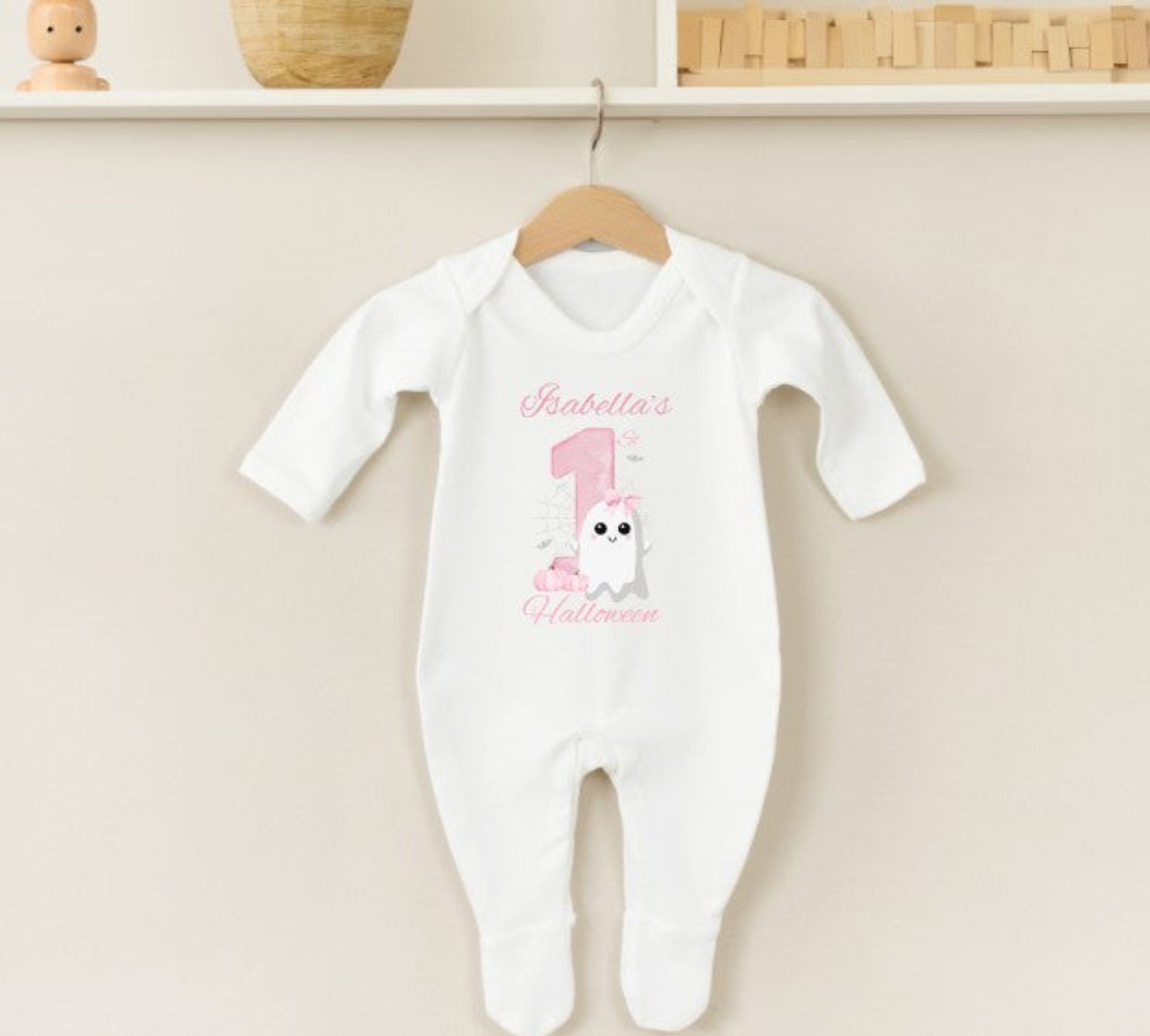 White baby onesie with personalised text on a beige background